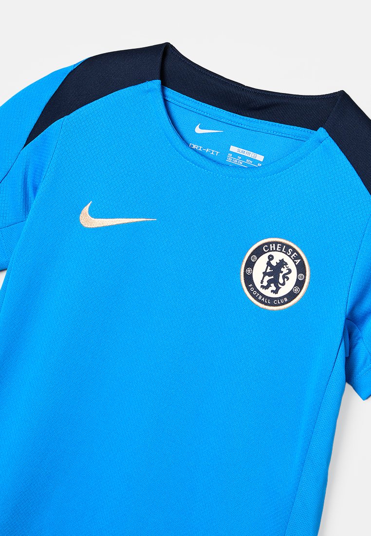 T-shirt de sport slim fit bleu Nike Dri-FIT avec des panneaux d'épaule noirs et le logo du Chelsea Football Club sur la poitrine.
