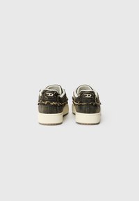 Baskets grises foncées avec une texture effilochée, semelle en caoutchouc beige, languette ronde et onglet de talon avec marque. Présente un design bas.