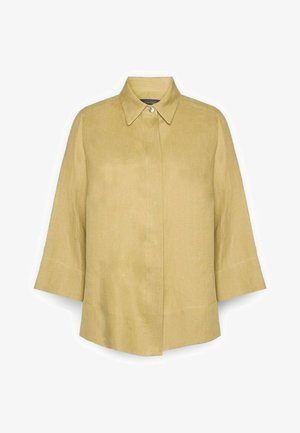 Camisa beige de manga tres cuartos con un botón visible en el cuello y una tapeta oculta en la parte frontal.