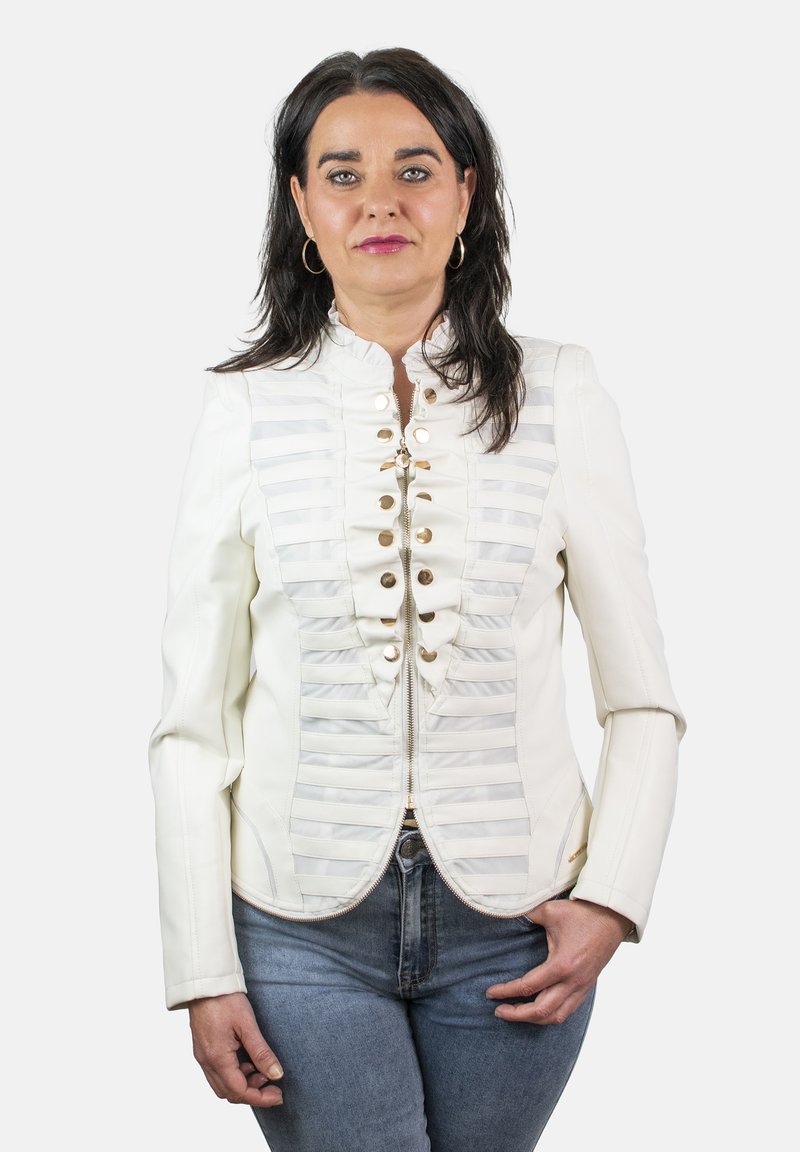 Chaqueta blanca a medida con rayas horizontales, botones dorados y un diseño ajustado. Se lleva sobre un vaquero azul. Textura suave y forma estructurada.