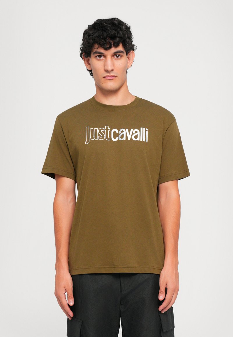 Alyvuogių spalvos medvilnės marškinėliai trumpomis rankovėmis, apvaliu kaklu ir ryškiu baltu grafiniu logotipu "Just Cavalli" priekyje.