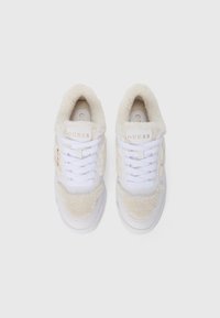 Weiße Sneakers mit einem kuscheligen, beigen Obermaterial, weißen Schnürsenkeln, einer weißen Zwischensohle und einem goldenen Logo auf der Zunge. Texturiertes Material an den Seiten.