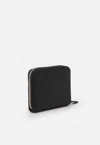 Portefeuille en cuir noir avec une surface texturée, de forme carrée, fermeture éclair en métal argenté et une petite tirette pour un accès facile.
