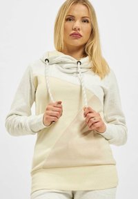 Helle Beigefarbene Kapuzenjacke aus weichem, meliertem Stoff. Sie verfügt über einen Bennet mit Kordelzügen, ein diagonales Color-Blocking-Design und lange Ärmel.