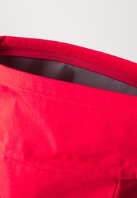 Red fabric bag with a smooth texture, featuring clean edges and stitching, open at the top revealing a gray interior lining.