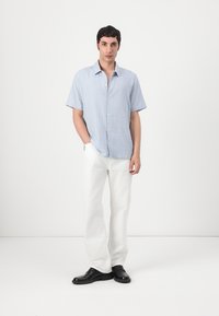Rövid ujjú, világoskék kockás ing, begombolva; fehér nadrággal és fekete fűzős cipővel párosítva. Minimalista design, sima textúra.