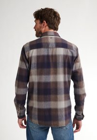 Camicia in flanella con un motivo a quadri nei toni del blu navy, marrone e grigio. Maniche lunghe, polsini con bottoni e orlo curvo.