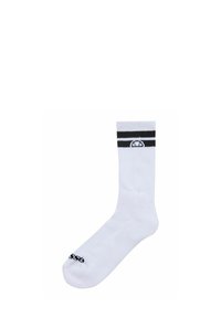 Witte sok met zwarte horizontale strepen aan de bovenkant, met een logo aan de bovenkant en tekst nabij de teen. Glad oppervlakte, typisch sportief ontwerp.