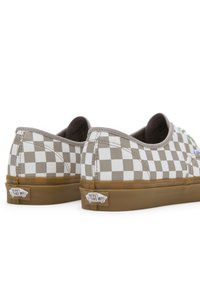 Scarpe in tela con un motivo a scacchi beige e bianco, suola in gomma e linguetta sul tallone, con il logo Vans sul lato.