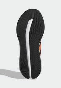 Zwarte rubberen sneakerzool met een gestructureerde profiel, witte middenzool en oranje accenten langs de zijkanten. Glad en duurzaam met duidelijke groeven.