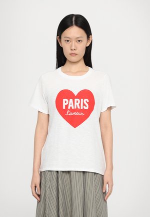 T-shirt en coton blanc avec un grand motif en forme de cœur rouge, portant le mot "PARIS" en lettres blanches en gras et "l'amour" en cursive en dessous.
