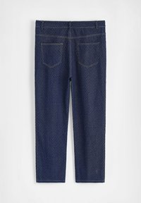 Pantalons capri en denim bleu foncé avec un motif texturé, dotés de deux poches arrière et de coutures jaunes le long des coutures.