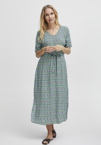 Maxiklänning med ett blått och grönt blommönster, korta ärmar, V-ringning och midjeband för justerbar passform. Mjuk tyg.