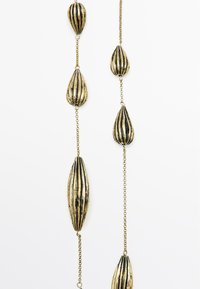 Gouden halsketting met langwerpige, druppelvormige schakels met verticale zwarte strepen, verbonden door een fijne ketting.