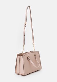 Borsa strutturata rosa chiaro con due manici corti, tracolla lunghe regolabile con catene dorate, mostrata su sfondo bianco.