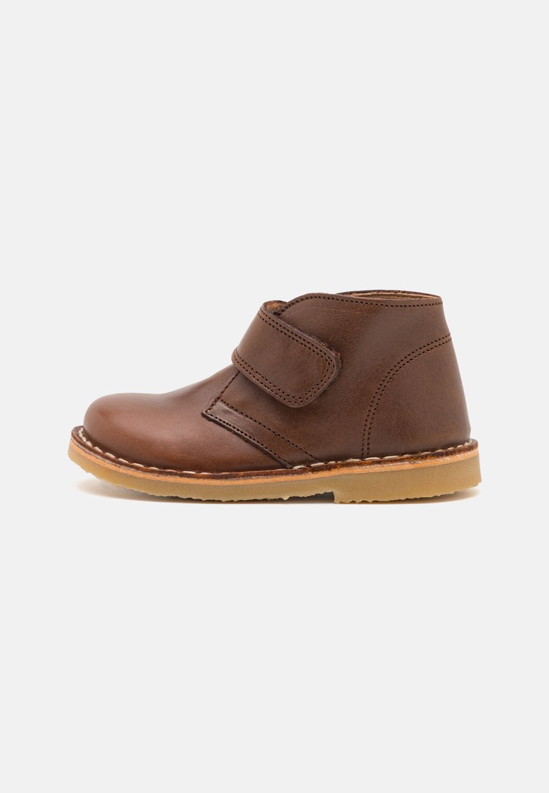 Brown leather ankle boot with a side Velcro strap, round toe, tan rubber sole, and stitched detailing.