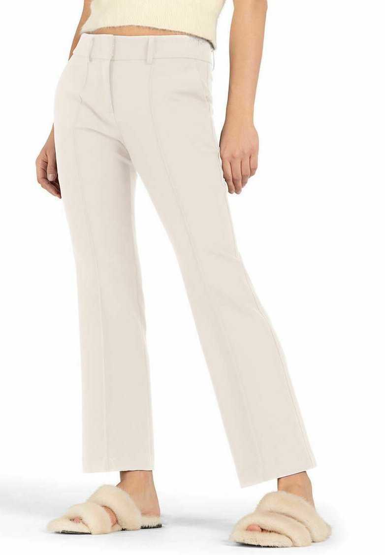 Beige flared trousers with front seams, flat front waistband, and clean-cut hem. Paired with fuzzy slide sandals in a light tan color.