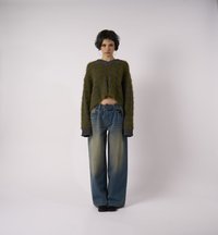 Πλεκτή πράσινη και γκρι κοντή μπλούζα με μακριά μανίκια σε συνδυασμό με φαρδιά τζιν παντελόνια με μπλε ρίγες. Σημαντικά χαρακτηριστικά: ψηλή μέση και φαρδιά εφαρμογή.