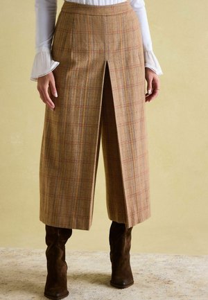 Karierte Culottes in Brauntönen, mit einem mittelhohen Bund, vorderem Schlitzdetail und taillierter Passform, kombiniert mit braunen Wildleder-Stiefeln.
