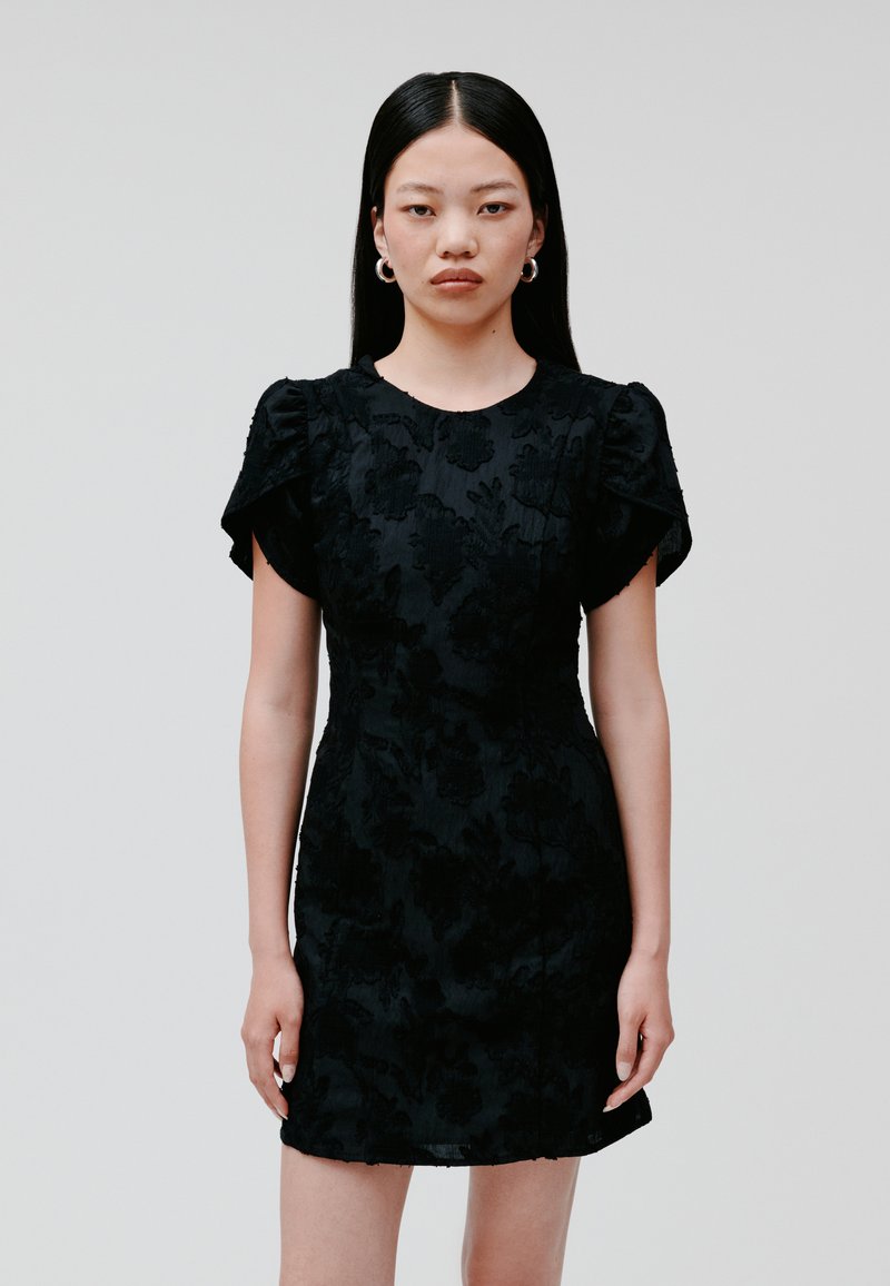 Black dress with short puff sleeves, floral textured pattern, fitted silhouette, and a round neckline, displayed against a plain background.
