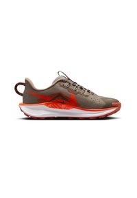 Zapatilla de running beige con parte superior de malla, acentos naranjas, agujetas negras y una entresuela blanca. Presenta una suela texturizada para mayor tracción.