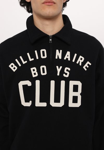 Μαύρος φλις πόλο με υψηλό γιακά, που διαθέτει μεγάλο, ραγισμένο λευκό κείμενο "BILLIONAIRE BOYS CLUB" και κλείσιμο με φερμουάρ στον λαιμό.