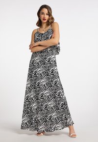Maxikleid im Schwarz-Weiß-Zebra-Print, mit dünnen Trägern, einer fließenden Silhouette und rüschendetails entlang des Ausschnitts.
