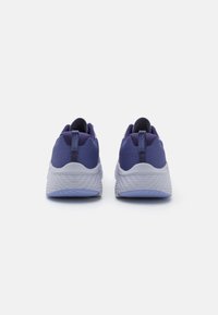 Baskets de sport violettes avec un dessus texturé, une semelle intermédiaire blanche et une semelle extérieure violet clair. Elles sont équipées d'une languette à l'arrière pour un enfilage facile.