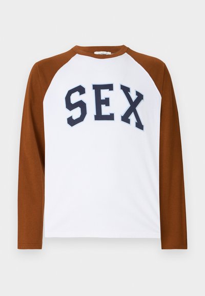 Langärmliges Raglan-T-Shirt mit weißem Körper und braunen Ärmeln, mit fetten marineblauen Buchstaben, die "SEX" über die Brust spellen.