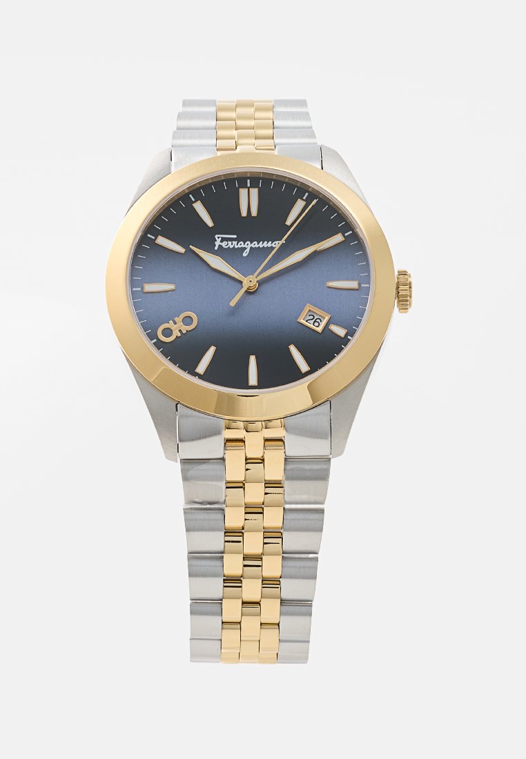 Montre analogique avec un cadran bleu, des accents dorés, un boîtier en acier inoxydable et un bracelet en métal bicolore, avec une fenêtre de date à 3 heures.