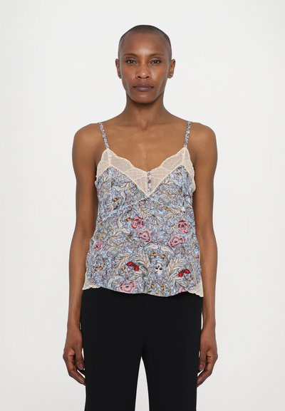 Camisole à motif floral en bleu clair avec dentelle, présentant un col en V et des boutons délicats, associé à un pantalon noir.