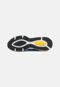 Semelle de chaussure avec une bande de roulement en caoutchouc noir, blanc et jaune, conçue pour la traction et le soutien, montrée sur un fond gris clair uni.