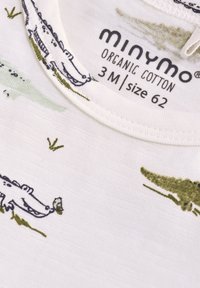 Ekologisk bomullsbody i krämfärg med gröna krokodiltryck. Har rund halsringning och textur med ett subtilt mönster. Storlek 62.