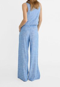 Modrý lněný mix bezrukávový cropped top, který je spárován s kalhotami širokého střihu, s texturovaným povrchem a elastickým pasem.