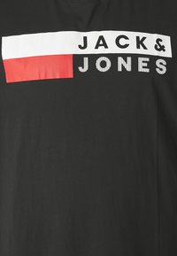 Black t-shirt featuring a prominent graphic with the text "JACK & JONES" in white and black stripes, and a red rectangular accent.