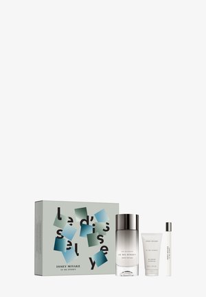 Set regalo di fragranze con una bottiglia di vetro trasparente con tappo argento, un tubo di lozione bianca e un piccolo spray da viaggio, tutti in confezione brandizzata.