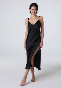 Vestito da notte in raso nero con dettagli in pizzo, scollatura a V profonda, spalline regolabili e uno spacco fino alla coscia, creando una silhouette elegante.
