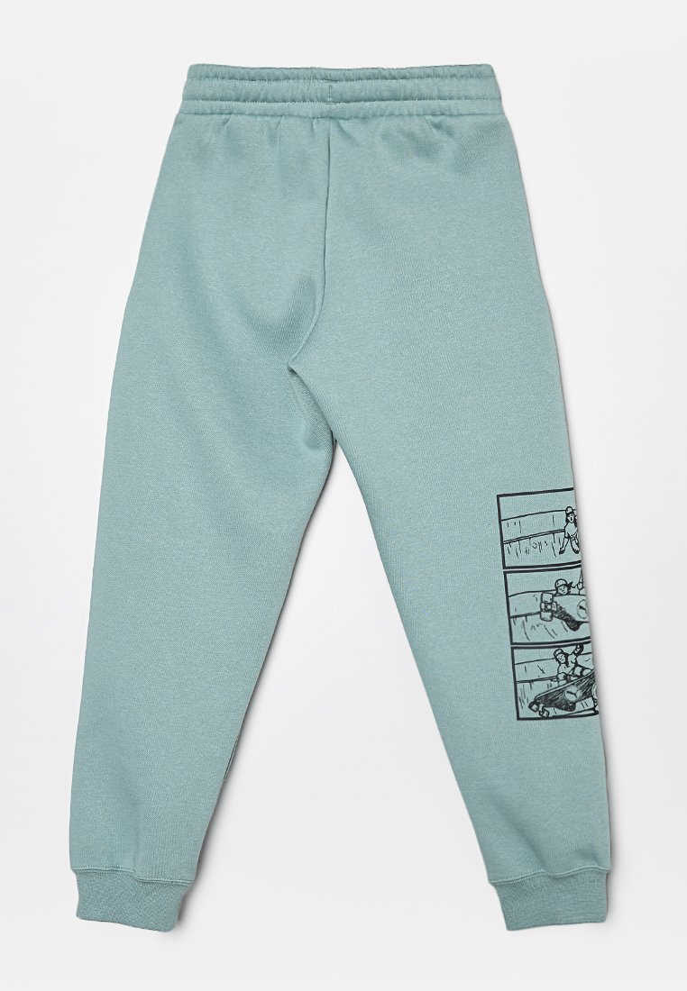 Pantaloni jogger di un blu teal chiaro realizzati in tessuto morbido, con un design in stile fumetto sulla gamba inferiore e una vita elastica con polsini aderenti.