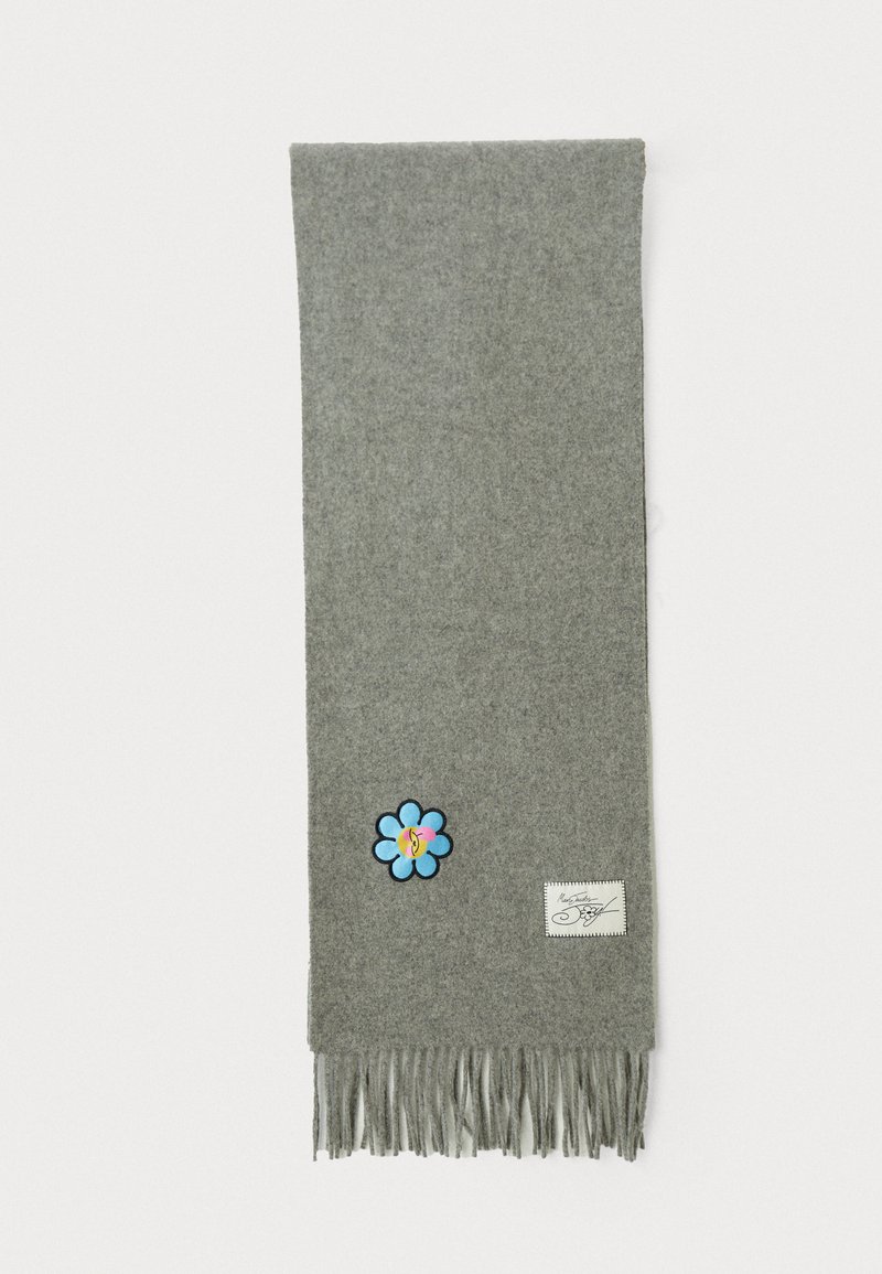 Grå uldscarf med frynset kant, prydet med en blå blomsterapplikation og et mærke med sort syning. Blød tekstur og enkelt design.