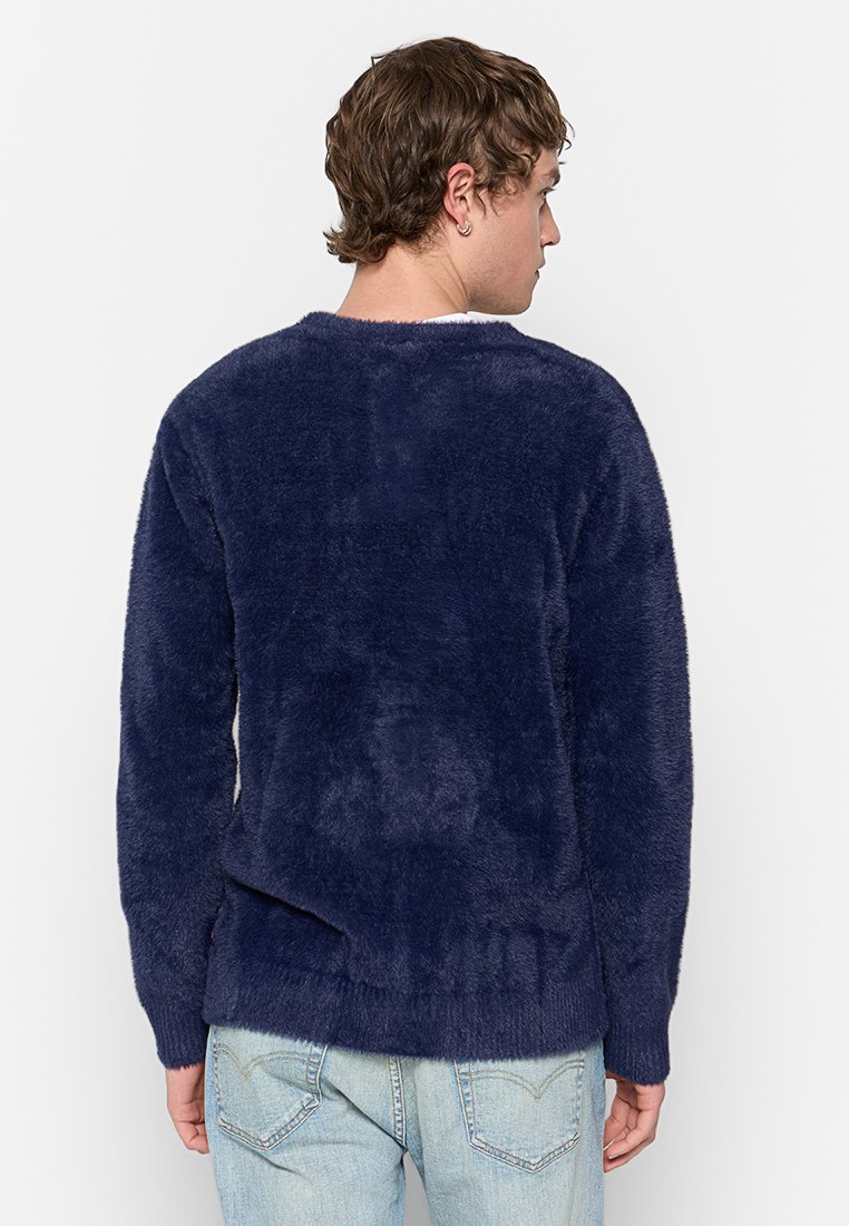 Pull en maille bleu marine, à col rond et manches longues, avec une texture douce et une coupe décontractée. Aucune motif ou accent visible.