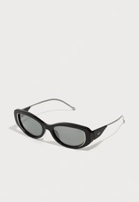 Black sunglasses with a sleek plastic frame, oval lenses, silver metal temples, and a distinctive logo on the side.