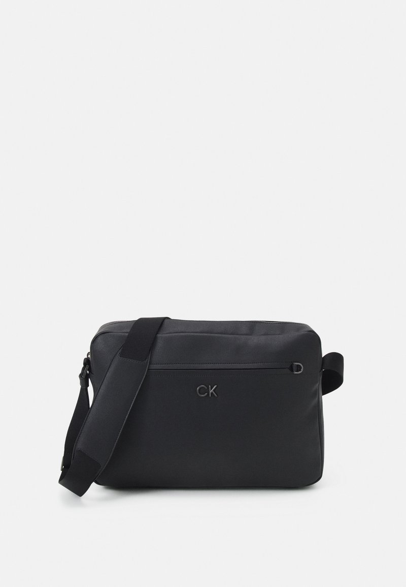 Borsa a tracolla nera con finitura in tessuto liscio, dotata di una tasca con zip frontale e una tracolla regolabile. Logo impresso sulla parte anteriore.