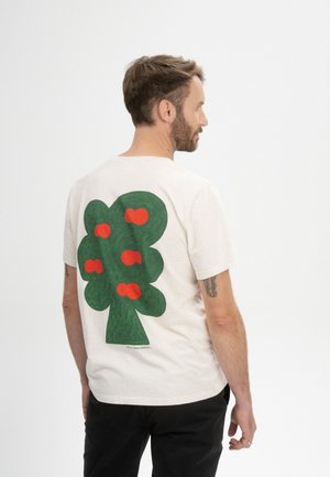 Lichtbeige katoenen t-shirt met een grote groene boomegrafiek met rode accenten op de achterkant. Korte mouwen en een relaxte pasvorm.