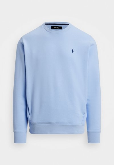 Sweatshirt bleu clair en tissu doux. Il présente un col rond, des manches longues et un petit logo brodé sur la poitrine.