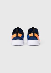 Para niebiesko-pomarańczowych sneakersów na slip-on z białymi podeszwami, widoczna z tyłu na jednolitym jasnoszarym tle.