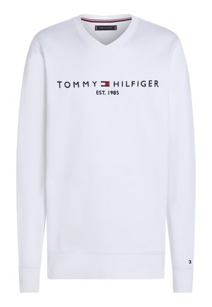 Sweat-shirt blanc à manches longues avec col en V, portant le texte "Tommy Hilfiger EST. 1985" et le logo drapeau sur la poitrine, ainsi qu'un petit logo sur le poignet gauche.