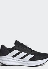 Chaussure de course athlétique noire et blanche avec trois bandes blanches sur le côté et une semelle blanche amortissante nommée Cloudfoam.