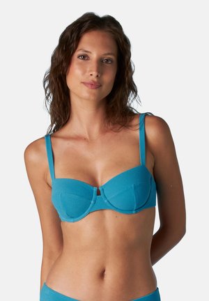 Brasiletta azzurra chiara con un design strutturato, dotata di coppe imbottite, spalline regolabili e una texture liscia. Senza decorazioni né motivi.