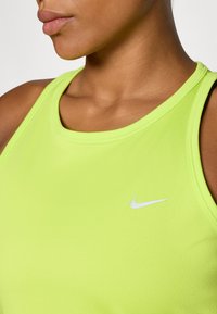 Neon grøn Nike sportstanktop med rund halsudskæring, der har flade sømme og et lille hvidt logo på venstre bryst.