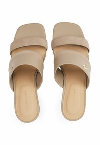 Beige Sandalen mit zwei breiten Riemen; einer glatt, der andere aus strukturiertem Wildleder. Mit einem goldenen Logo-Akzent und einem quadratischen Zehendesign.